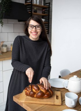 Mutfakta gri elbiseli, siyah saçlı güzel bir kadın. Modern beyaz mutfak.