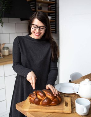 Mutfakta gri elbiseli, siyah saçlı güzel bir kadın. Modern beyaz mutfak.