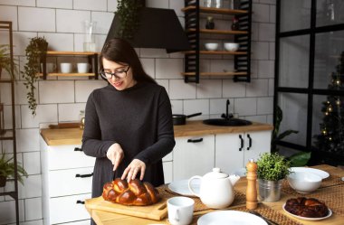 Mutfakta gri elbiseli, siyah saçlı güzel bir kadın. Modern beyaz mutfak.