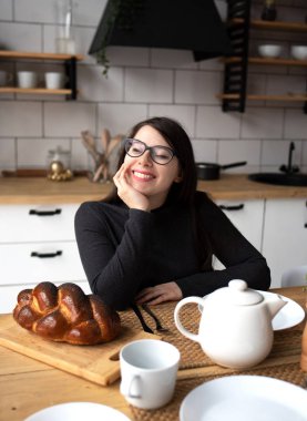 Mutfakta gri elbiseli, siyah saçlı güzel bir kadın. Modern beyaz mutfak.