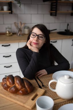 Mutfakta gri elbiseli, siyah saçlı güzel bir kadın. Modern beyaz mutfak.