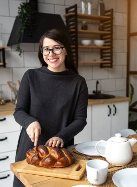 Mutfakta gri elbiseli, siyah saçlı güzel bir kadın. Modern beyaz mutfak.