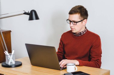 Masasının başında gömlekgiyen genç bir adam. Yakışıklı bir adam evde çalışıyor..