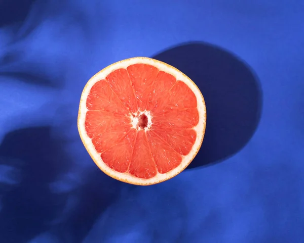 Bright red grapefruit in a section on a blue background.