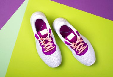 White women's sneakers on a bright green background.