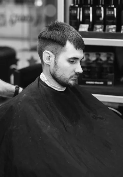 Um jovem numa barbearia. cara na moda com cabelo escuro . — Fotografia de Stock