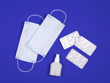 C oronavirüsünün P intikamı. Tıbbi maskeler, vitaminler, mavi arka planda antiseptik..
