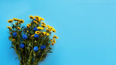 Mavi arka planda mavi ve sarı çiçekli bir buket. Metin için boş alan