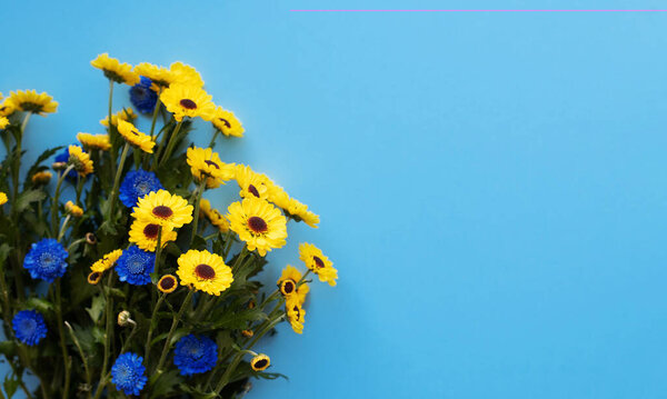 Bouquet with blue and yellow flowers on a blue background. Free space for text