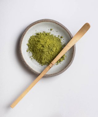 Açık gri arka planda tahta kaşık. Toz halinde kibrit yeşil çay. Sağlıklı yaşam tarzı