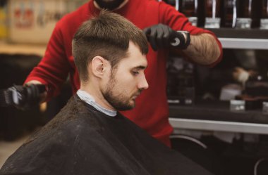 A young man in a Barber shop. Trendy guy with dark hair.