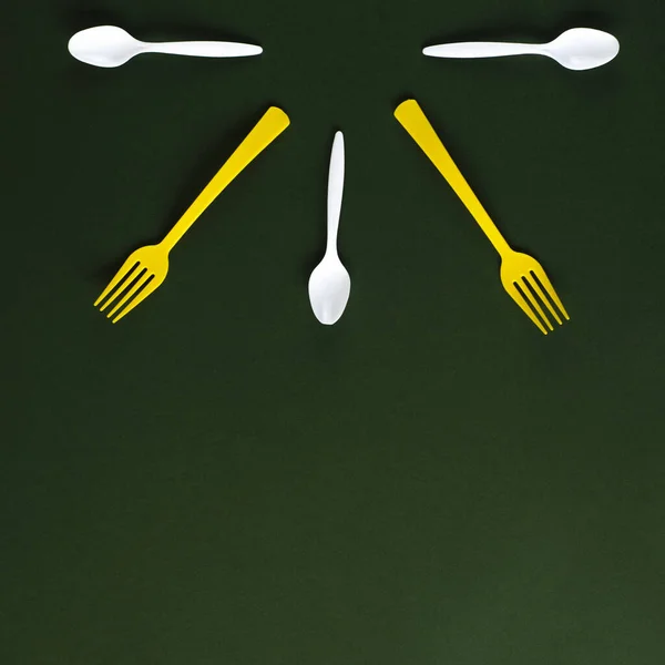 Tenedores de plástico amarillo y cucharas blancas sobre un fondo verde . —  Fotos de Stock