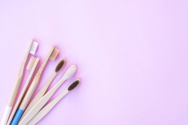 Pembe arka planda ekolojik ahşap diş fırçaları.