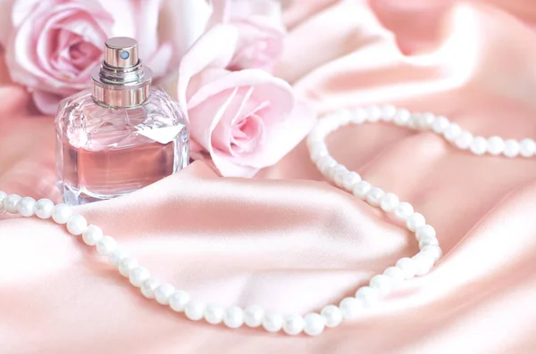 Kobiece perfumy, róża, perły na różowym jedwabiu. — Zdjęcie stockowe