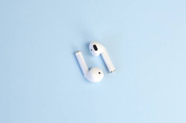 Mavi arka planda kablosuz beyaz kulaklık. Bluetooth kulaklıklar. Yeni Teknolojiler Eğilimi.