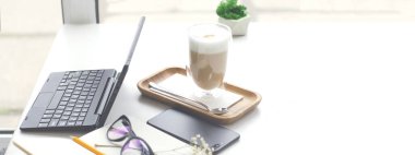 Dizüstü bilgisayarı, akıllı telefonu, not defteri ve kahve makinesi olan bir masa. Telgraf işi. Çevrimiçi emir. Çevrimiçi öğrenme. Site için pankart.