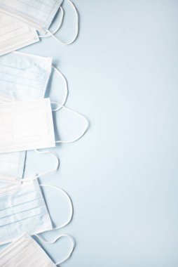 Açık mavi arka planda bir sürü tıbbi maske var. Tıp minimalist kavramı. Dikey konum.