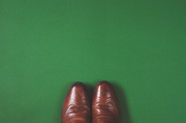 Yeşil arka planda kahverengi erkek çizmeleri. Metin için bir yer var.