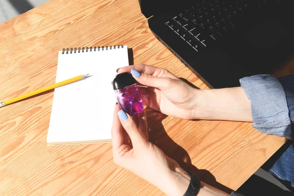 Girl holds a sanitizer for hands. Workplace.