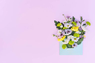 Çiçek aranjmanı pembe arka planda bir zarfın içinde. Metin için bir yer var.