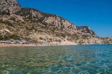 Yaz aylarında Yunanistan 'ın Rodos kentinde turistlerin olduğu Tsambika plajı. Malzemesiz Kraliyet fotoğrafı..