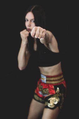 Uzun boylu kız boks pozisyonunda yumruk atıyor, Muay Thai boks pantolonu ve siyah bluz giyiyor. Malzemesiz Kraliyet fotoğrafı..