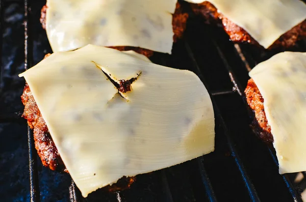 Hambúrgueres de queijo em uma grelha — Fotografia de Stock