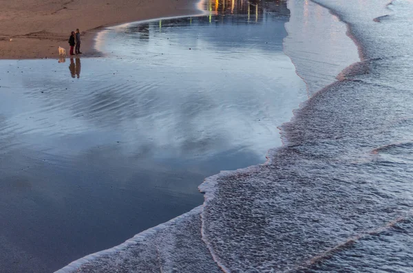 Gente mirando las olas del mar al atardecer en San Sebastián, España — Foto de Stock