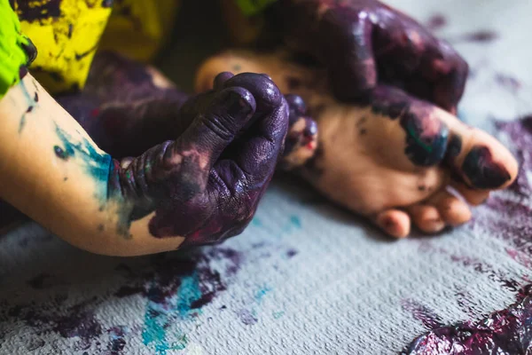 Pequeño niño manos y pies cubiertos de múltiples colores — Foto de Stock