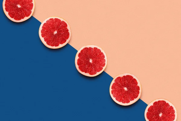 Plastry grejpfruta na klasycznym tle niebiesko-brzoskwiniowym. Kolor letniego roku 2020 — Zdjęcie stockowe