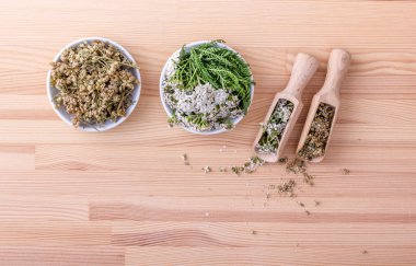 civanperçemi çayı / Top iki kase görünümünü ve kaşık taze ve kurutulmuş çiçeklerin ve civanperçemi ahşap arka plan ile yaprakları 