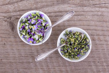 Menekşe heartsease / Üstten Görünüm alanı yumuşak ahşap arka plan üzerinde taze ve kurutulmuş çiçekler ile iki beyaz kase 