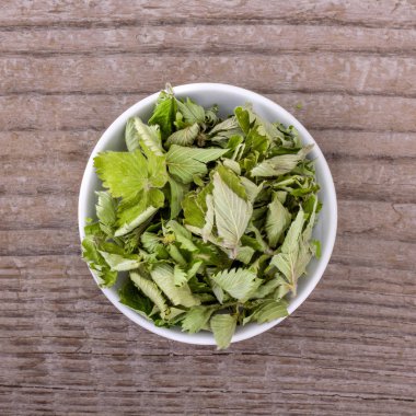 çilek yaprakları bitkisel çay / kurutulmuş çilek ile porselen kase yaprakları bir ahşap arka plan üzerinde