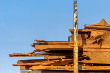 Dalgaların eski, paslı metal parçaları mavi gökyüzüne karşı. 