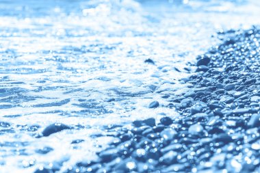 Mavi ıslak çakıl taşları ve deniz kenarında su.