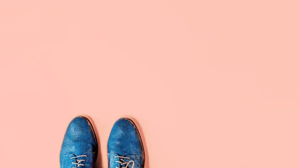 Pair of shiny blue shoes on peach background