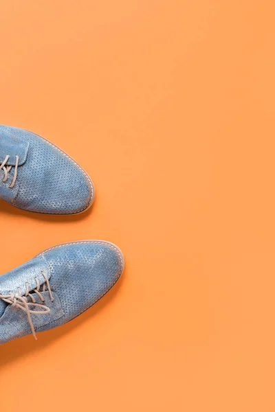 Pair of shiny blue shoes on orange background