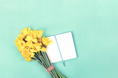 Nane yeşili üzerinde açık defter olan nergis buketi