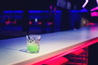 Gece kulübü ışıklarında yeşil neon kokteyl cam