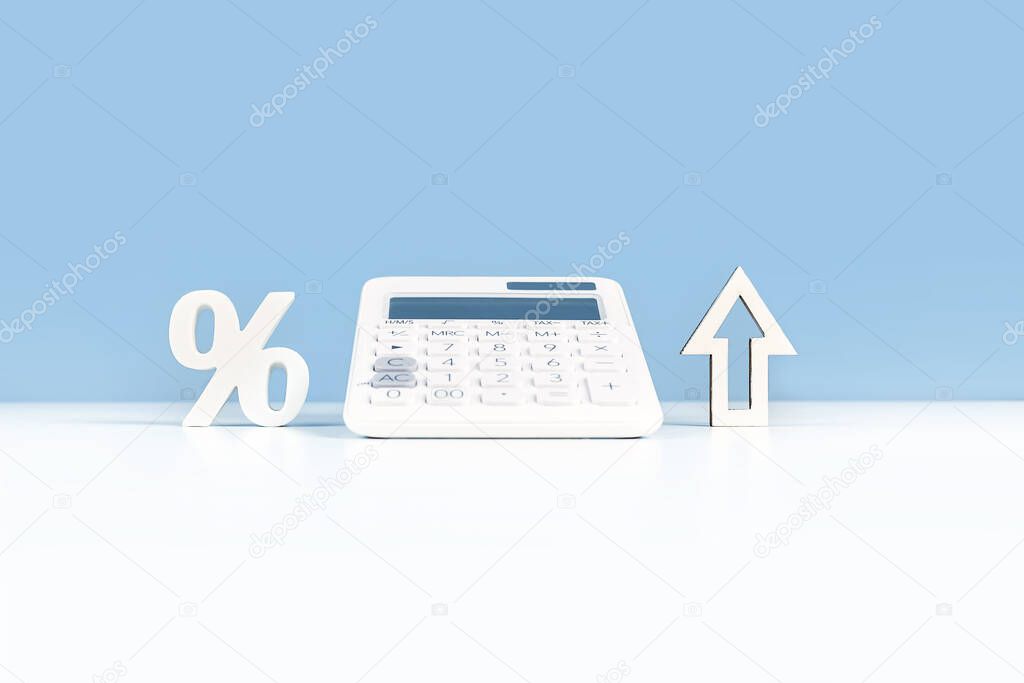 Business or education growth development and success concept banner. White calculator with percentage sign and an arrow on white office or home desk with blue background. Copy space. Startup investment