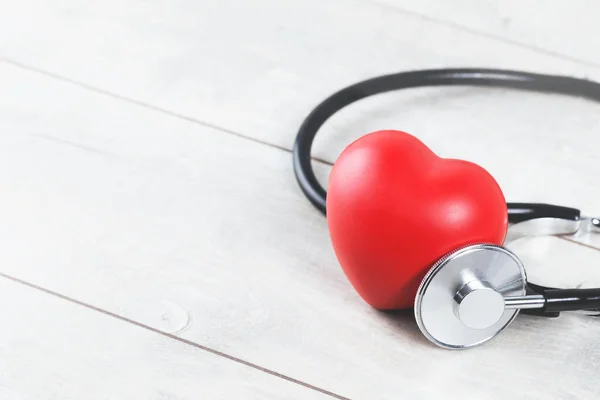 Kırmızı kalp, gri ahşap masada fonendoskopla yaklaş. Kardiyo durumu, obezite ya da kilo yönetimi olan sağlıklı bir yaşam tarzı. Boşluğu kopyala