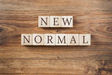 Tahta yapı taşları üzerine yeni normal metin. COVID salgınından sonra yeni bir hayata ya da iş hayatına adapte olmak. Sosyal mesafeli kişisel hijyenle iş