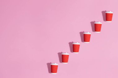 Pembe arkaplanda kağıt bardakların deseni.