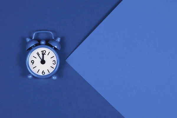 Blue alarm clock on trendy toned background. Stock Photo