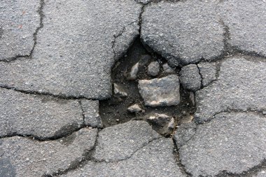 Yol çukuru ve asfalttaki çatlaklar yakın çekim makrosu. Arkaplan te