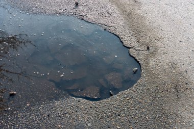 Yol çukuru su ile dolmuş, yakın plan. Arkaplan metni