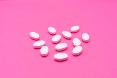 Beyaz oval haplar pembe arka planda yatıyor. Uzayı kopyala, makro