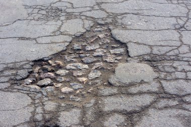 Yol çukuru ve asfalttaki çatlaklar yakın çekim makrosu. Arkaplan te