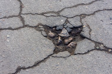 Yol çukuru ve asfalttaki çatlaklar yakın çekim makrosu. Arkaplan te