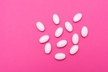 Beyaz oval haplar pembe arka planda yatıyor. Uzayı kopyala, makro